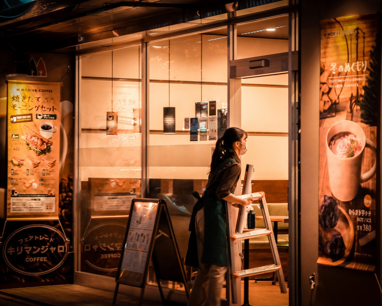 a woman standing outside of a coffee shop at night